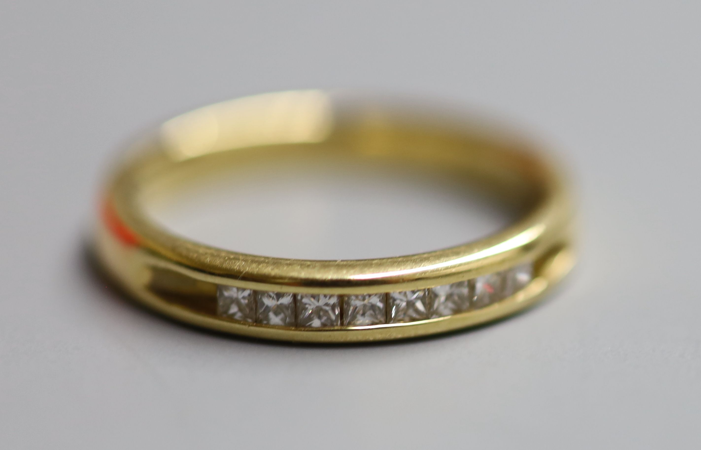 A modern 18ct gold and channel set eight stone diamond ring, size N/O, gross 4.4 grams.